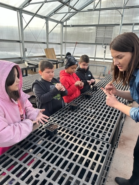 Teacher giving instruction to students about plants