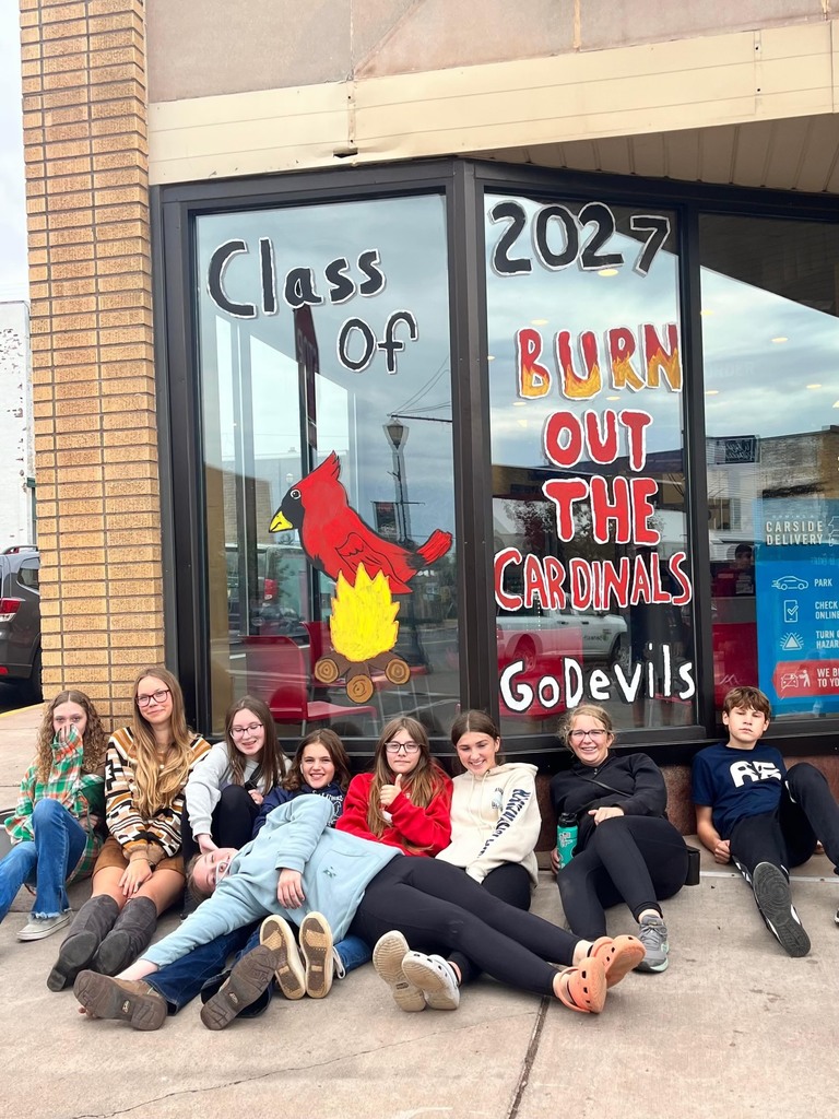 9 students in front of a decorated window for homecoming