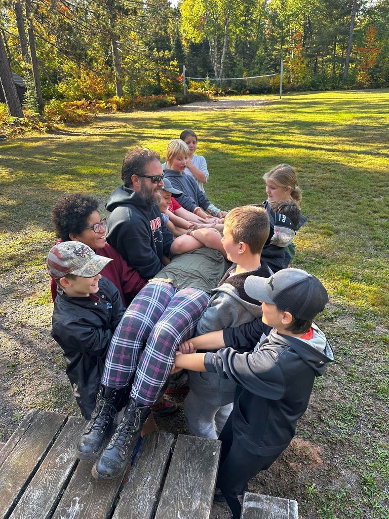 A teacher and some students support another student in a trust fall
