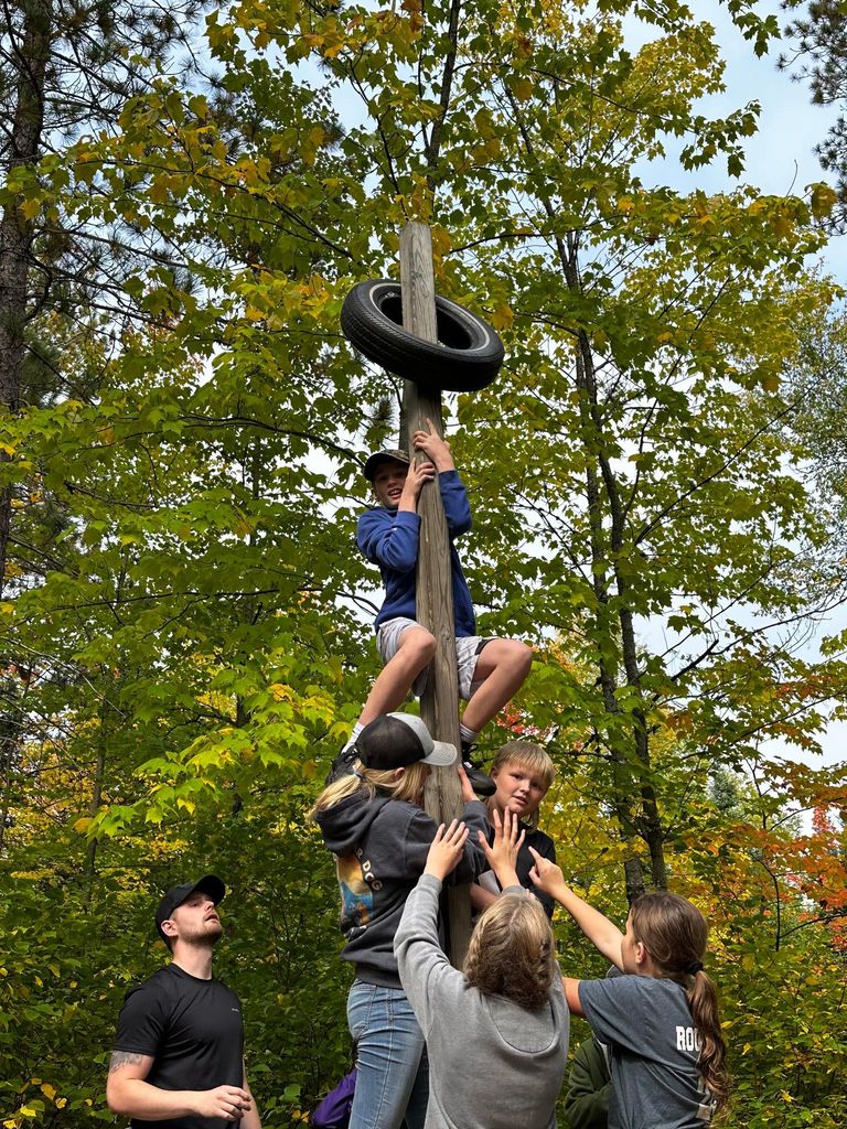 Students support each other to get up a pole